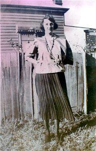 Lady standing near a fence beside a house, [n.d.]