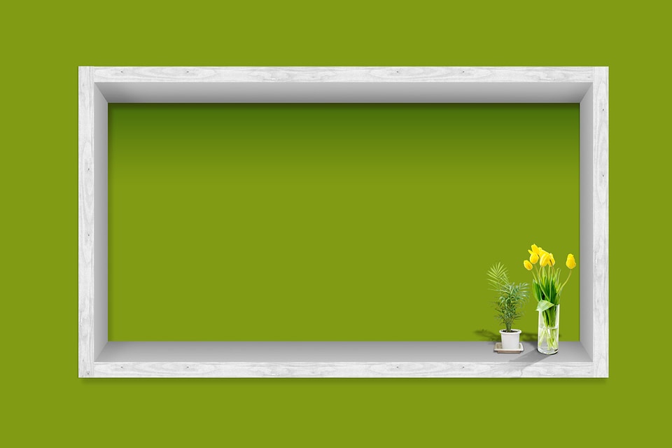 white frame with flower on the green wall