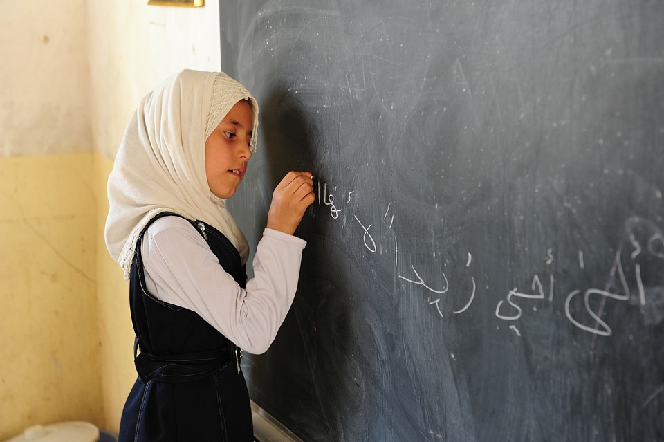 Girl writing math equations on a blackboard in class