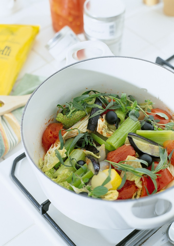 Pot on a stove with vegetables cut for making soup