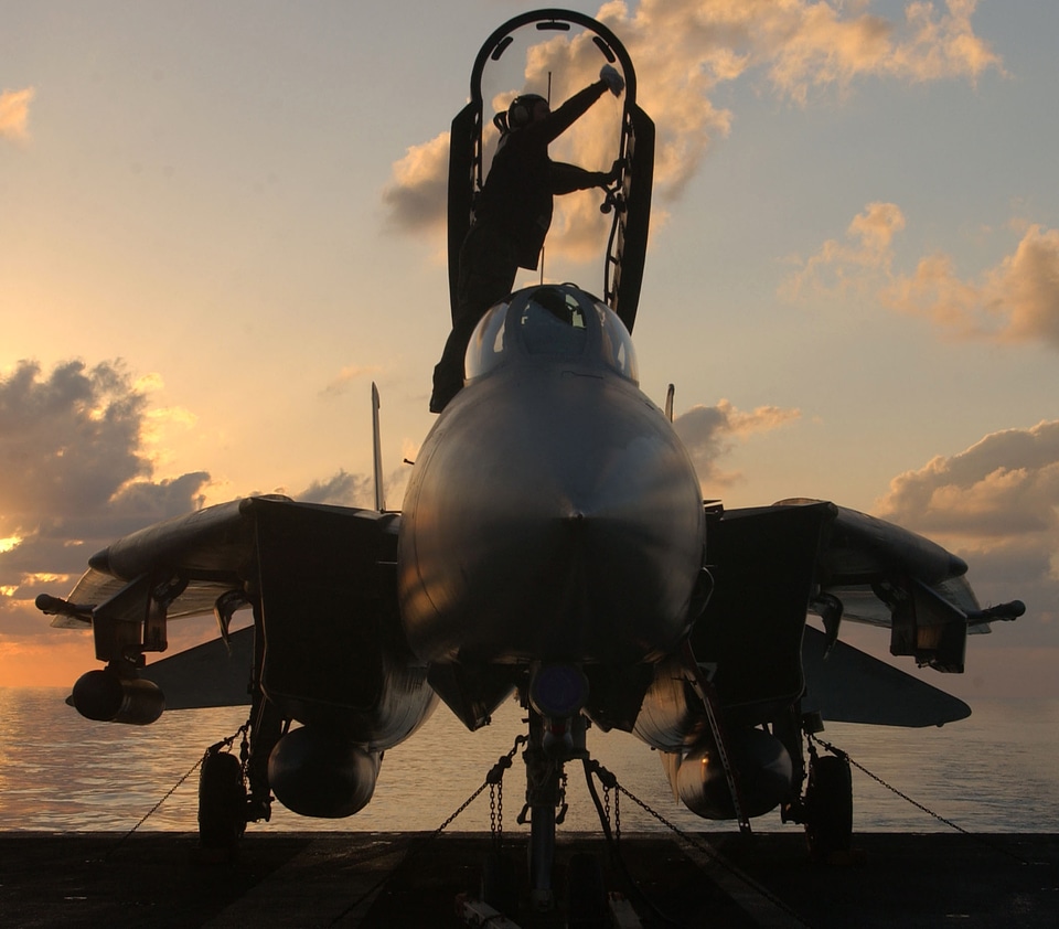 A crew member cleans a canopy on an F-14 Tomcat