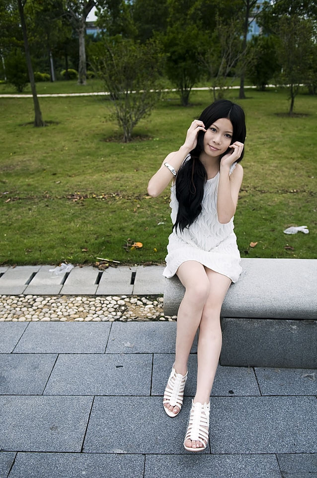 A Beautiful Chinese Girl Posing On A Bench Outdoors
