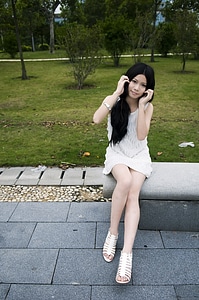 A Beautiful Chinese Girl Posing On A Bench Outdoors
