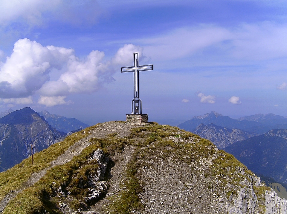 Stone cross and crucifix on an old chapel in the mountains