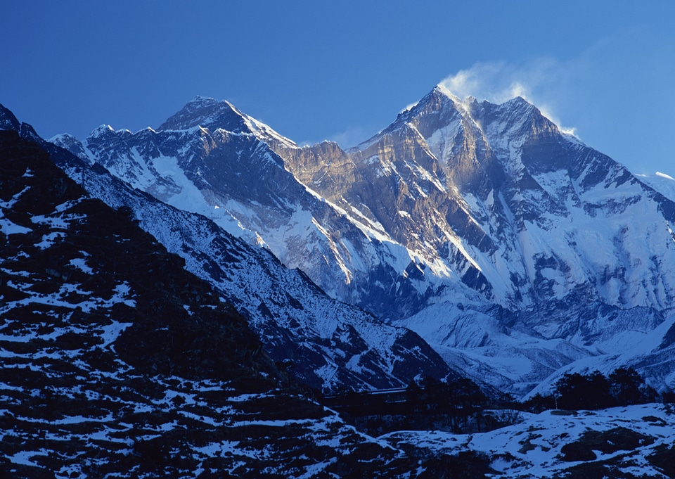wind blows snow away from a highlighted mountain peak