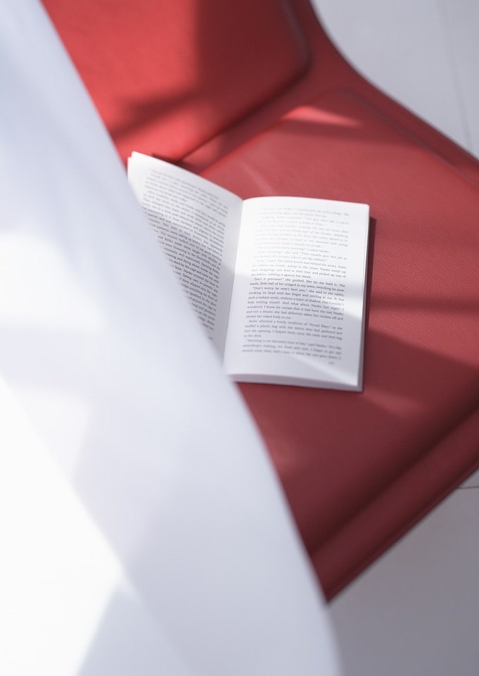 Book on red chair on curtain