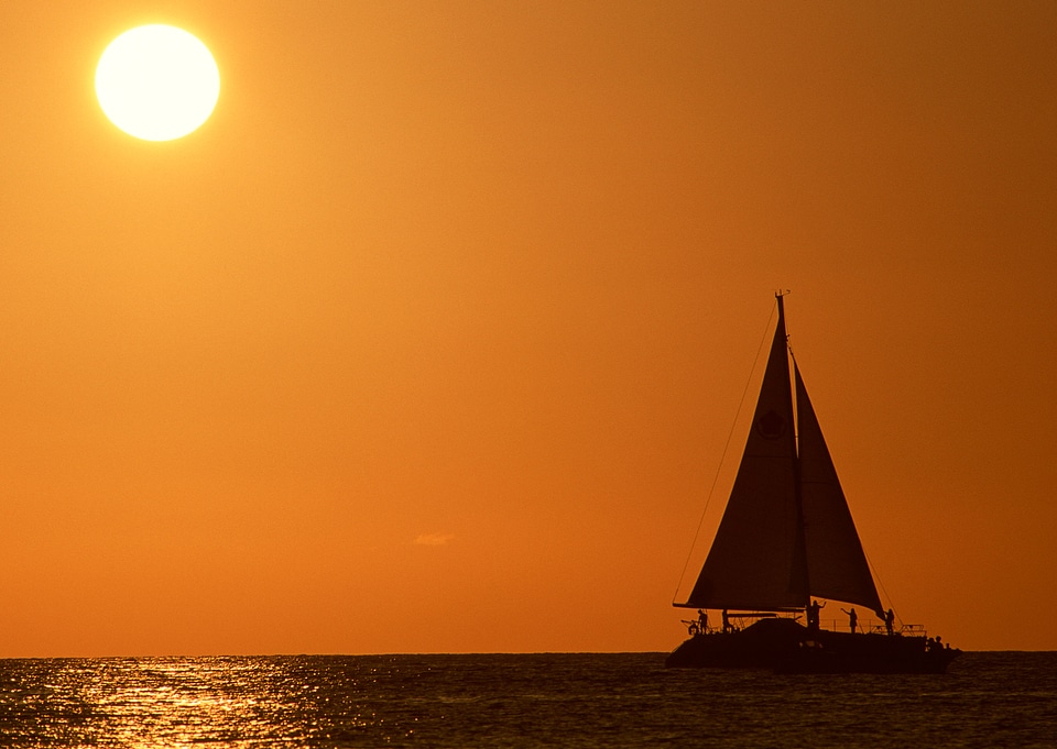 Sailing boats in silhouette against a tropical sunset