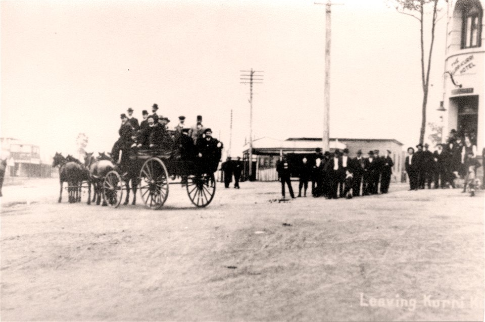 Leaving home. A horse-drawn wagon with multiple people aboard leaving from the Kurri Kurri Hiotel, Kurri Kurri, NSW, [n.d.]. They are being farewelled by a crowd outsife the hotel. photo