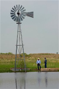 Windmill at stock tank on ranch with rancher and NRCS staff photo