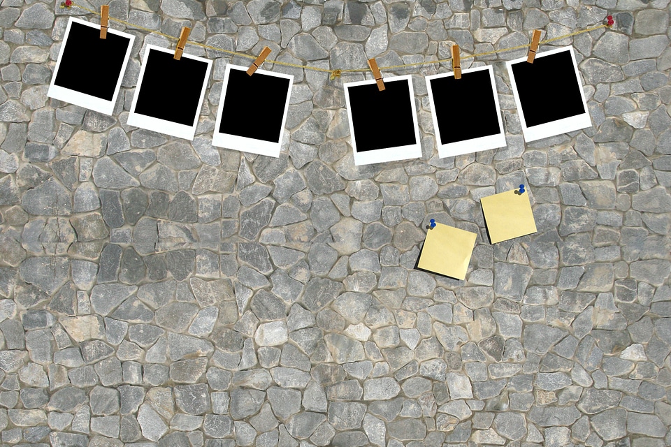 Blank photos hanging on a clothesline over wall