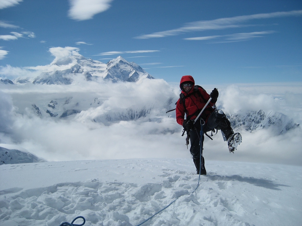 A lone mountaineer reach the top of a high mountain peak
