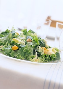 bowl of leafy green salad with olives, tomatoes