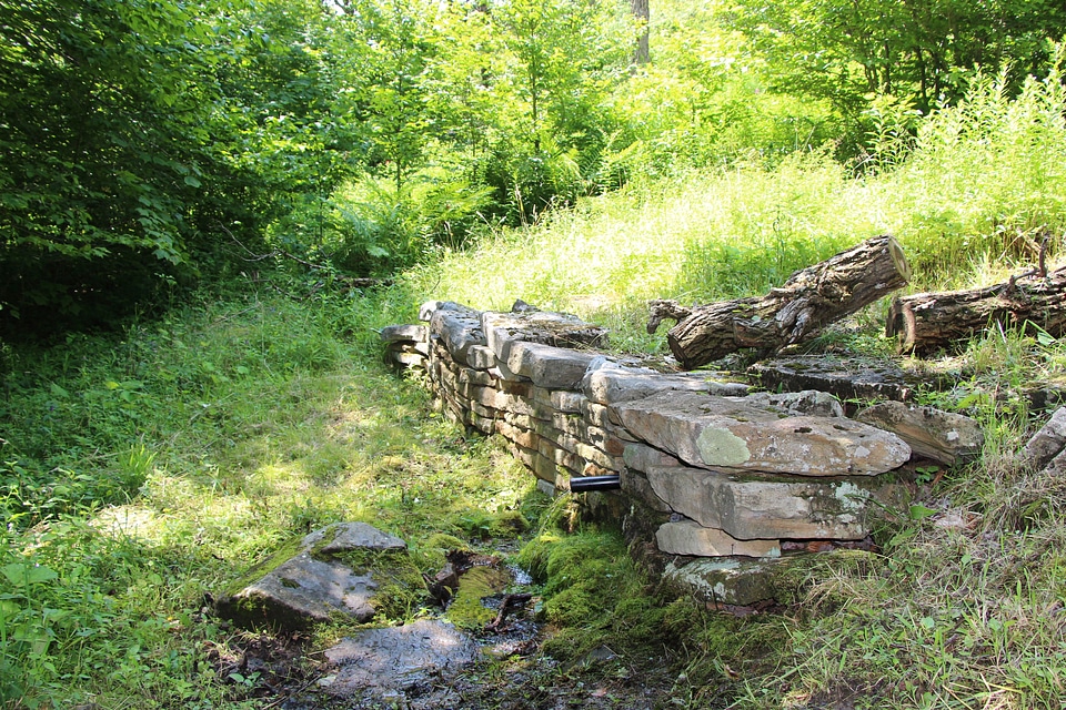 Water flowing from pipe against blurred mountain