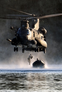 An Airman jumps out of an MH-47 Chinook helicopter photo