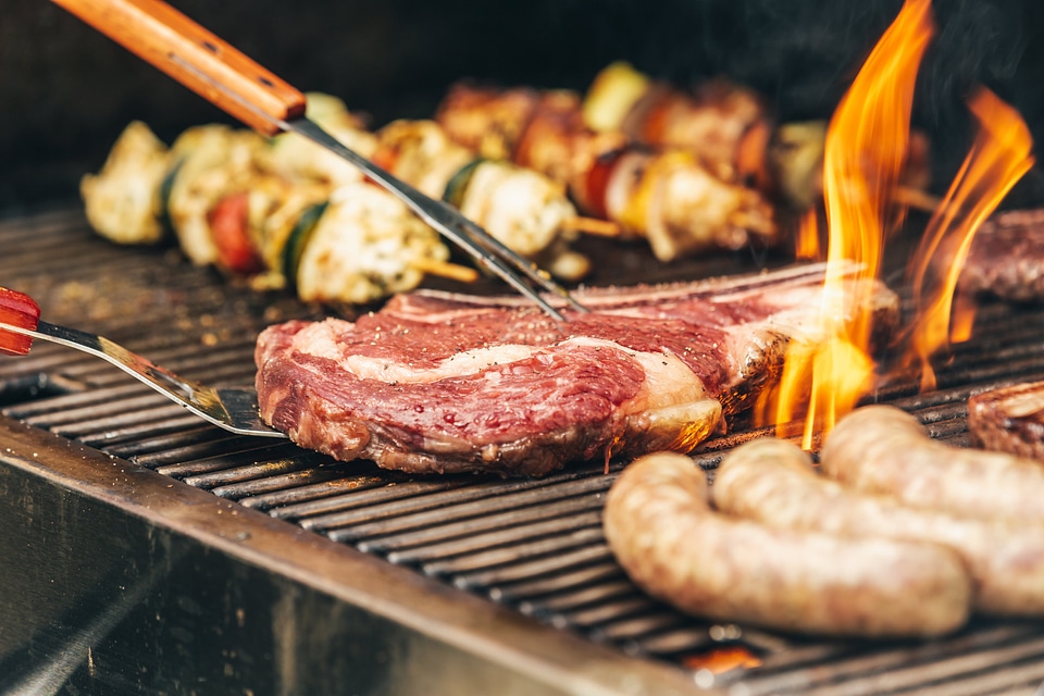 Flames lick the sides of a steak as it cooks on the grill