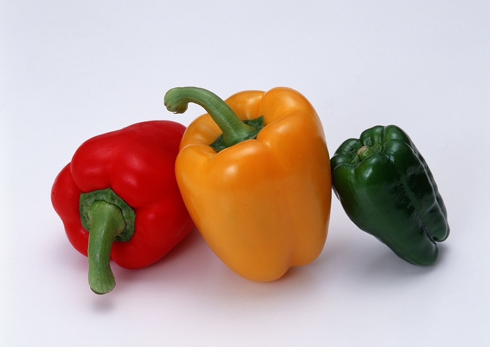 colored peppers over white background