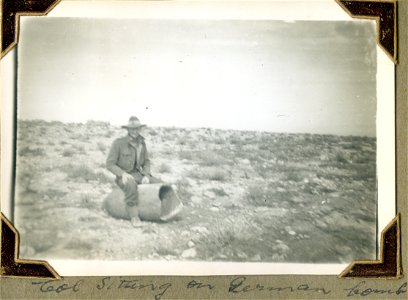 Col [Surname unknown] sitting on German bomb, North Africa