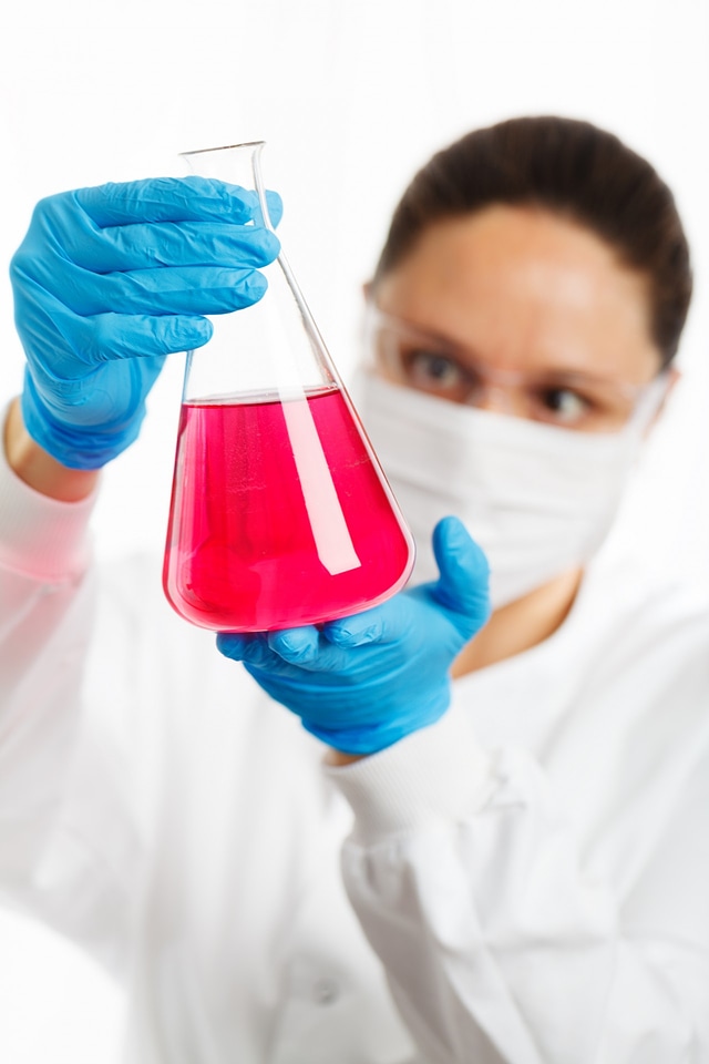 female researcher holding an Erlenmeyer flask with pink liquid photo
