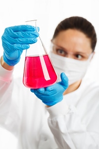 female researcher holding an Erlenmeyer flask with pink liquid