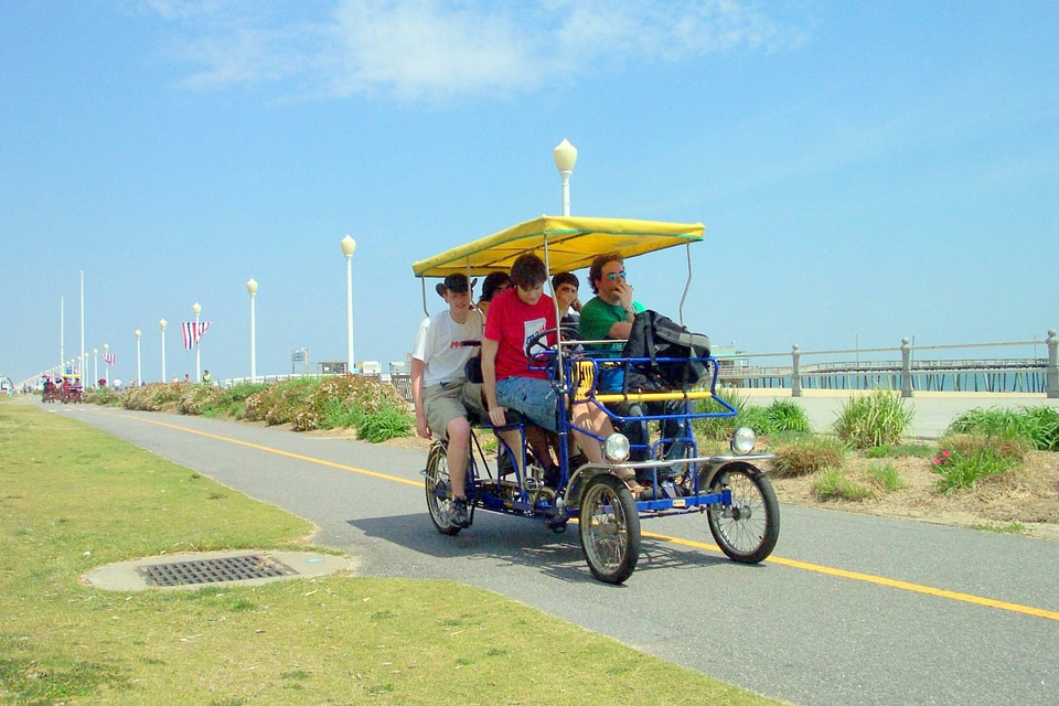 People riding a rental surrey on the Boardwalk in Virginia Beach