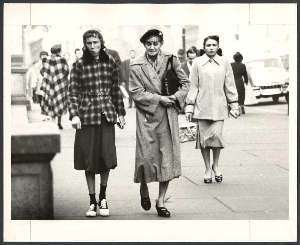 Two women, full-length portrait, walking on sidewalk in Fifth Avenue, in NYC