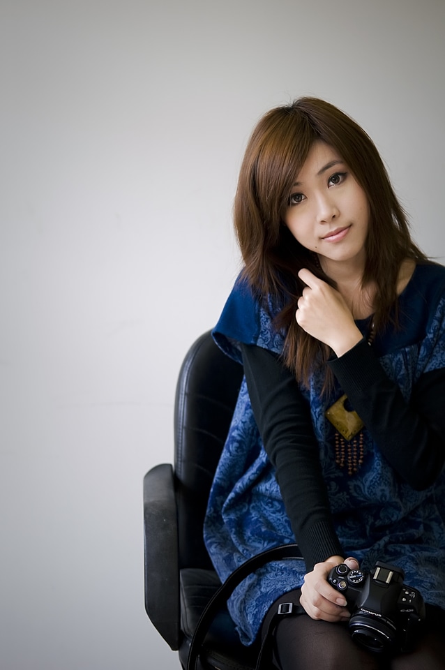 Chinese Girl Posing In A Chair With A Camera