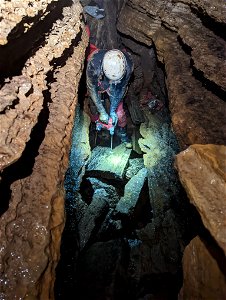 Man drills rock in cave photo