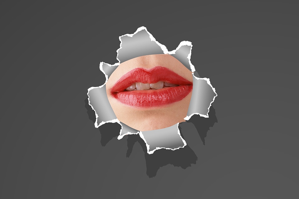 woman lip through a broken thin wall or torn paper