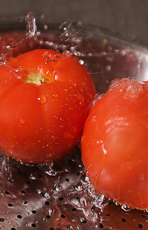 Two Fresh Tomatoes Being Washed Under Running Water