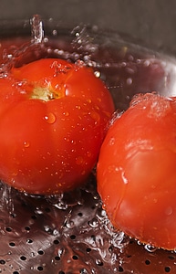 Two Fresh Tomatoes Being Washed Under Running Water