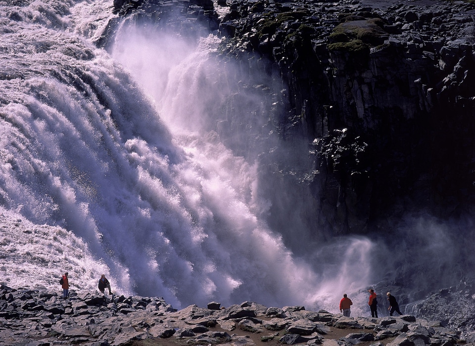 Tourist looking at the powerful waterfall of Dettifoss