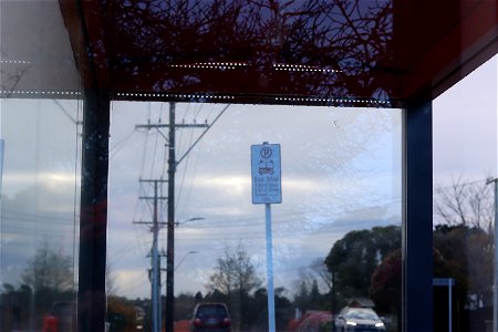Inside bus stop looking at bus stop sign, power lines, Ngāmotu New Plymouth, Taranaki, New Zealand