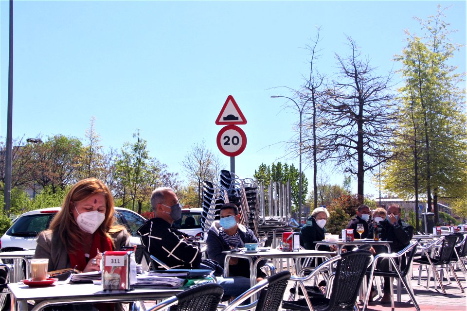 Plano general de una terraza de un bar con personas con mascarilla