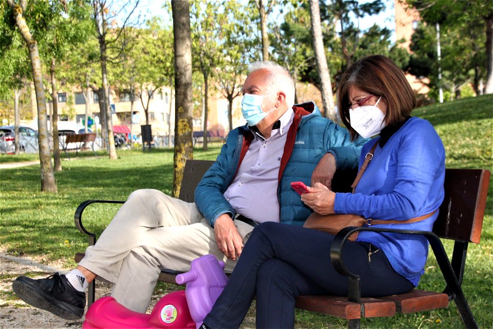 Plano medio de una pareja mayor sentada en un banco de un parque