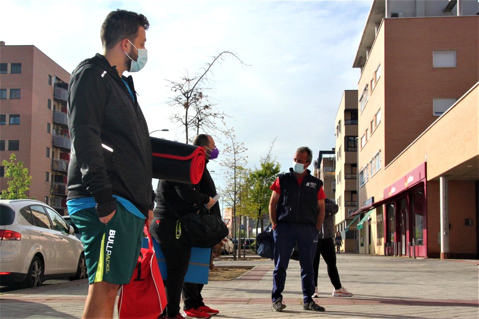 Plano americano de hombres con ropa deportiva esperando en una acera