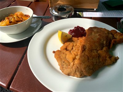 Schnitzel with fried potatoes, lemon and a dip raspberry