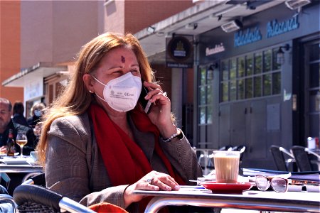 Mujer hablando por teléfono sentada en la terraza de un bar
