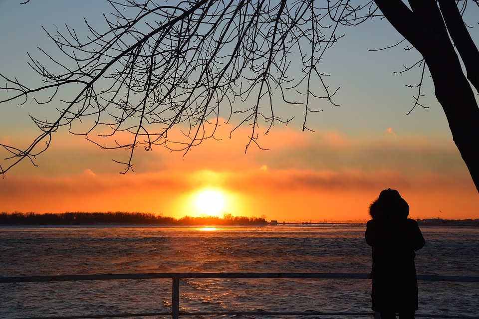 Young adult woman standing at orange yellow sunset