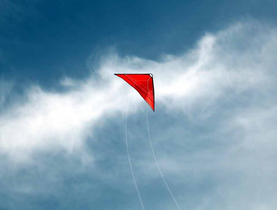 A red kite flying against a blue sky