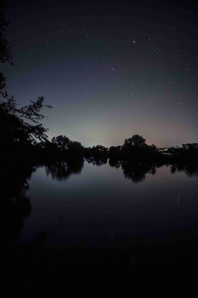 Night starry sky over the forest and the river