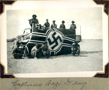 Captured Nazi flag, North Africa. Ten [Australian] soldiers displaying it.