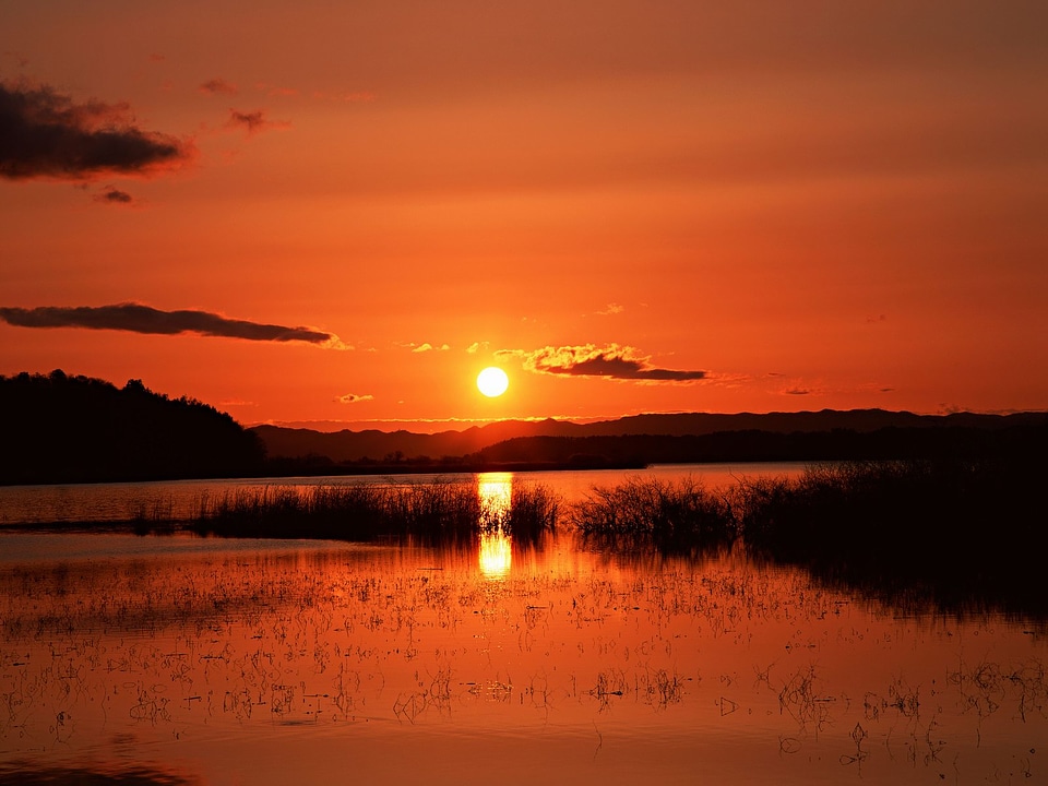 Sunset in huge mountains near lake with grass.