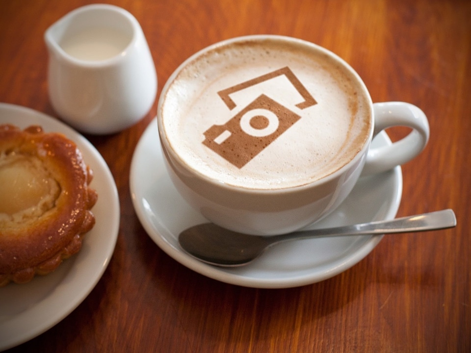 hot milk art coffee on wooden table Photo in old image style.