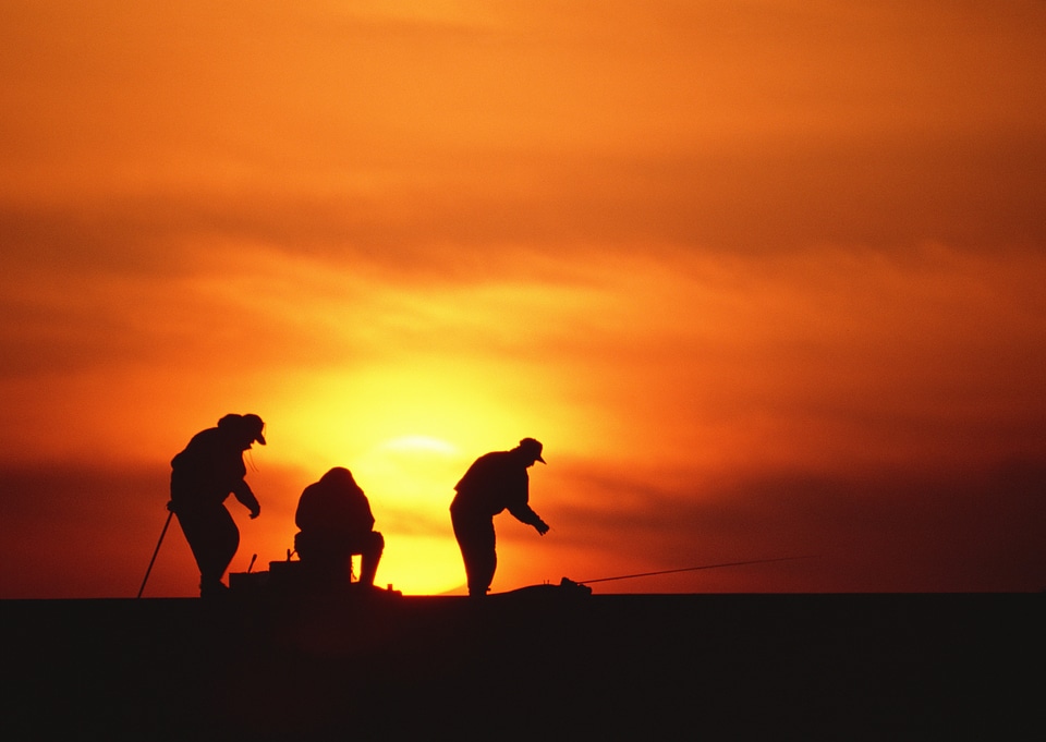 silhouette of fisherman by the ocean in sunrise photo