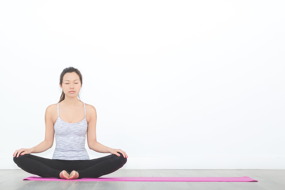 Woman in seated meditation pose on pink yoga mat photo