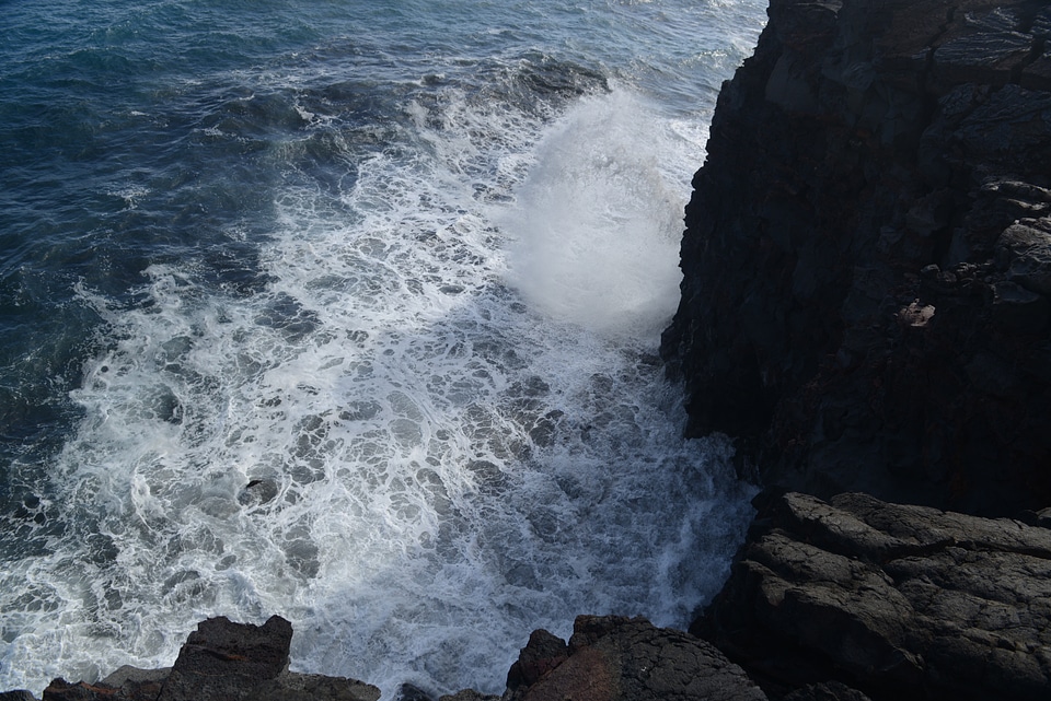 Waves crash along the black lava rock cliffs in the Hawaii