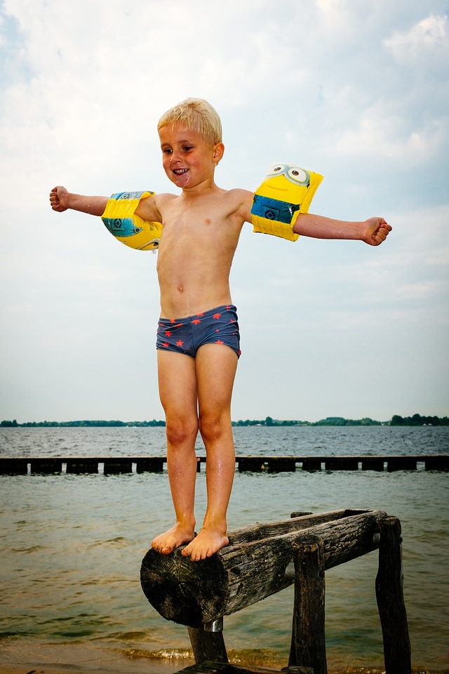 Laughing smiling young boy in blue water of the swimming