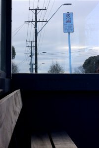 Inside bus shelter looking out at bus stop sign and sky Ngāmotu New Plymouth, Taranaki, New Zealand