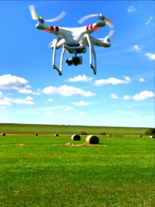 Look at that DJI Phantom 3 suspended in Blue Sky above Green Grass & Hay Bales in Lawrence, Kansas photo