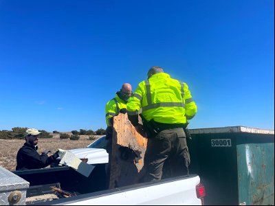 National Park Service employees transfer debris from truck to dumpster.